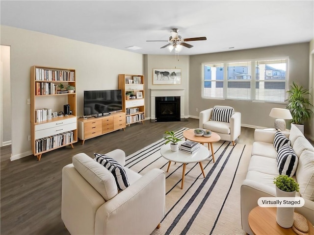 living area with baseboards, a ceiling fan, wood finished floors, and a fireplace