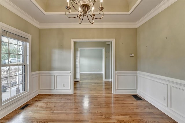 3426 Olivia Grace Way, Dacula, GA 30019 - unfurnished dining area featuring a chandelier, light wood finished floors, ornamental molding, a wainscoted wall, and a raised ceiling