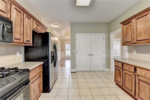 3426 Olivia Grace Way, Dacula, GA 30019 - kitchen featuring black appliances, brown cabinetry, light tile patterned floors, and wainscoting