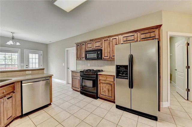 3426 Olivia Grace Way, Dacula, GA 30019 - kitchen with black appliances, brown cabinetry, a chandelier, decorative backsplash, and light countertops