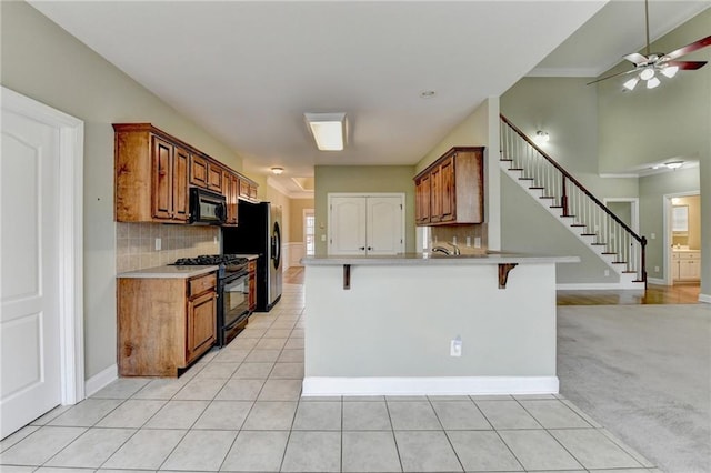 3426 Olivia Grace Way, Dacula, GA 30019 - kitchen featuring black appliances, brown cabinetry, a breakfast bar area, and light countertops