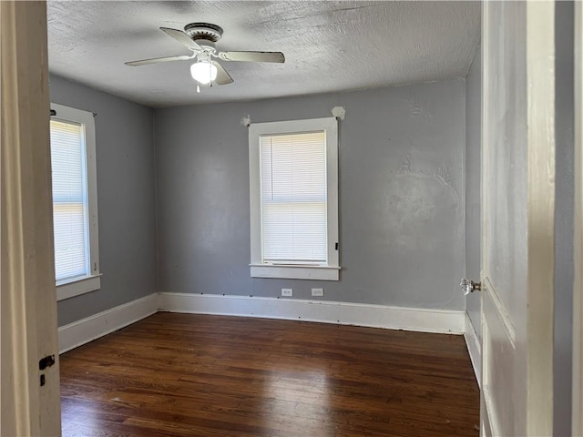 spare room featuring a healthy amount of sunlight, baseboards, and wood finished floors