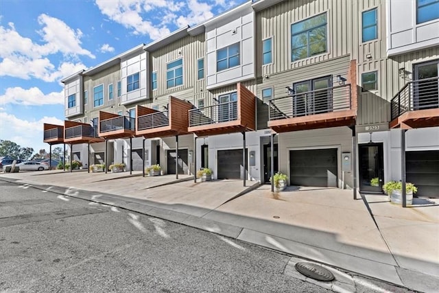 multi unit property featuring board and batten siding, an attached garage, driveway, and a residential view