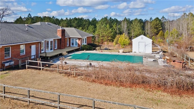 view of swimming pool with a wooden deck and a storage unit