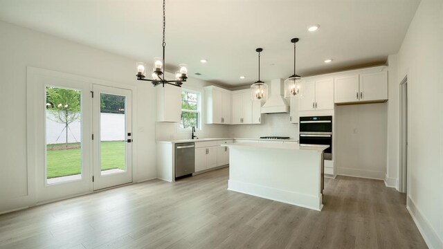 1514 Gatekeeper Ter, Marietta, GA 30066 - kitchen with stainless steel dishwasher, premium range hood, a chandelier, decorative backsplash, and light wood-style floors