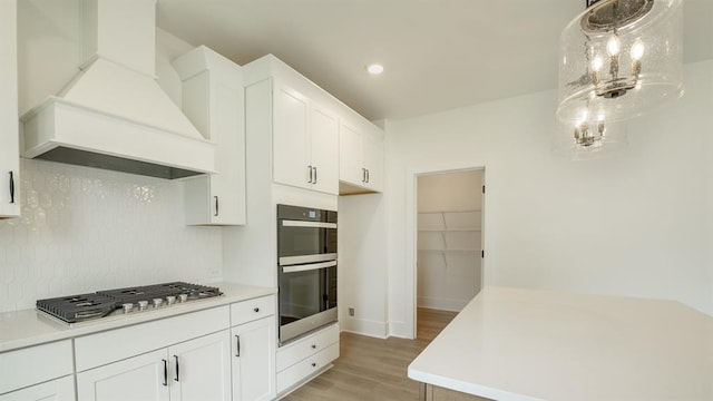 1514 Gatekeeper Ter, Marietta, GA 30066 - kitchen featuring custom range hood, stainless steel appliances, light wood finished floors, tasteful backsplash, and white cabinetry