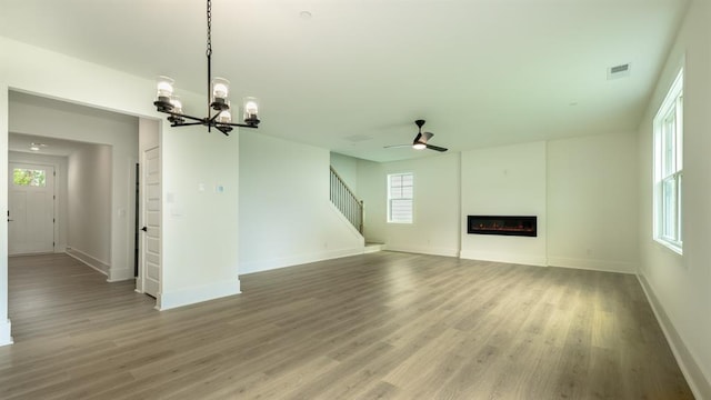 1514 Gatekeeper Ter, Marietta, GA 30066 - unfurnished living room with a ceiling fan, a chandelier, light wood finished floors, and baseboards