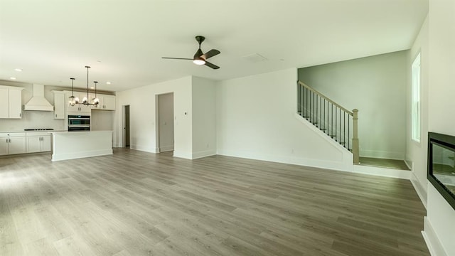 1514 Gatekeeper Ter, Marietta, GA 30066 - unfurnished living room featuring stairs, recessed lighting, ceiling fan, light wood finished floors, and a chandelier