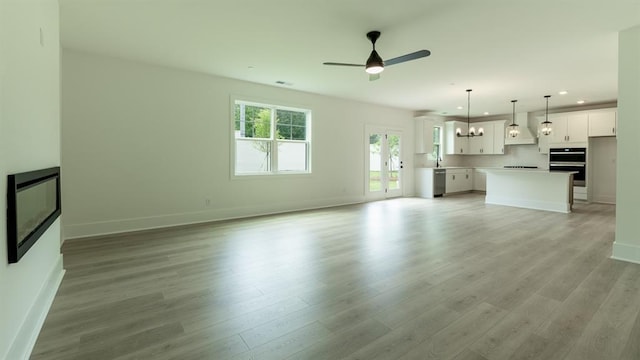 1514 Gatekeeper Ter, Marietta, GA 30066 - unfurnished living room featuring a ceiling fan, baseboards, recessed lighting, light wood-style flooring, and a chandelier