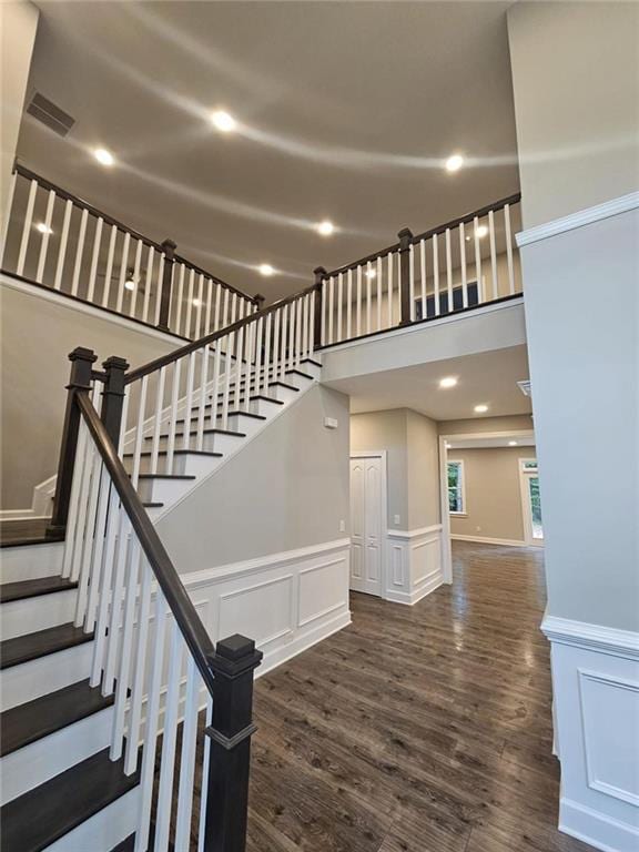 staircase featuring hardwood / wood-style flooring and a high ceiling