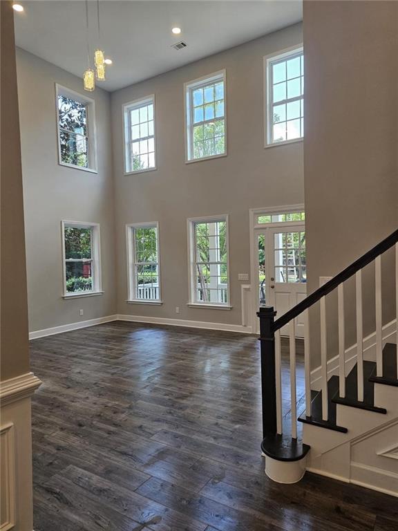 living room with dark wood-type flooring, a wealth of natural light, and a towering ceiling