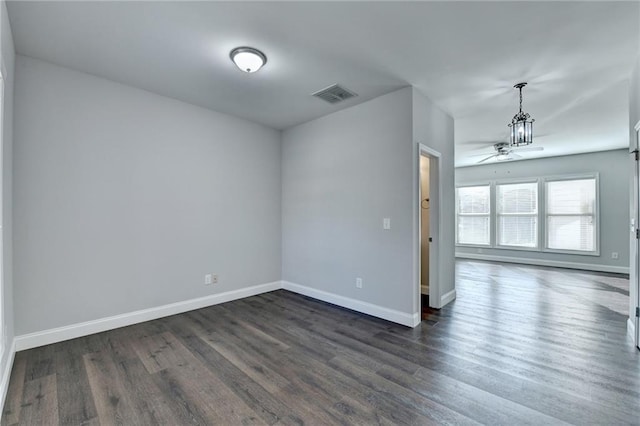 empty room featuring a ceiling fan, visible vents, dark wood finished floors, and baseboards