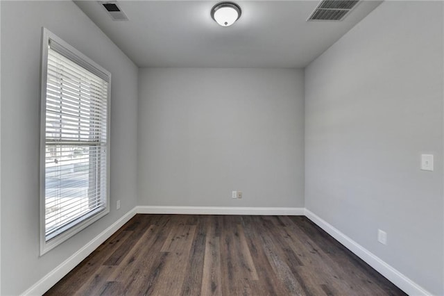 spare room featuring dark wood finished floors, visible vents, and baseboards