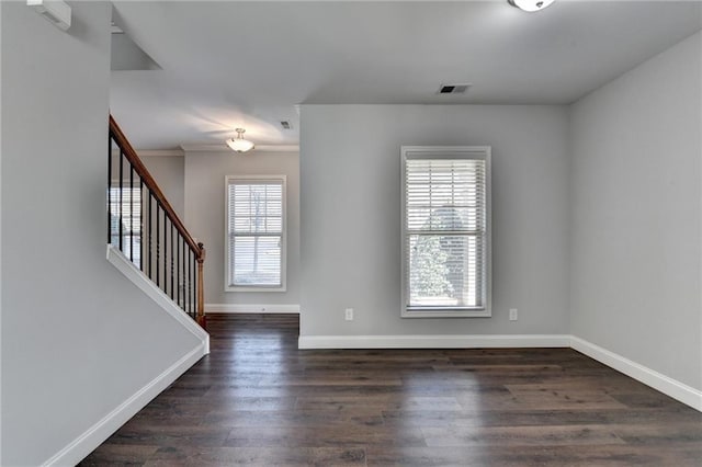 empty room with visible vents, baseboards, stairs, ornamental molding, and dark wood-style floors