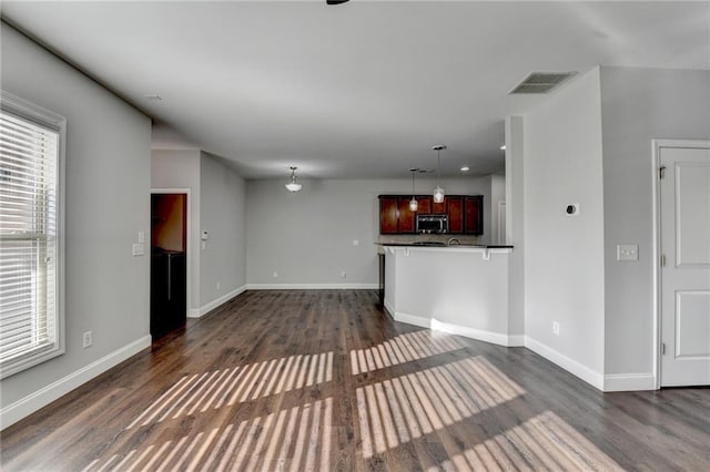 unfurnished living room with dark wood-style flooring, visible vents, and baseboards