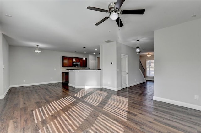 unfurnished living room with dark wood-style flooring and baseboards