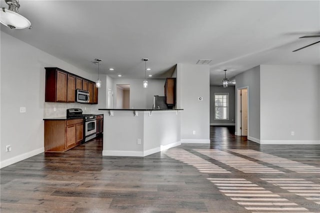 kitchen featuring open floor plan, appliances with stainless steel finishes, dark wood-style flooring, and dark countertops