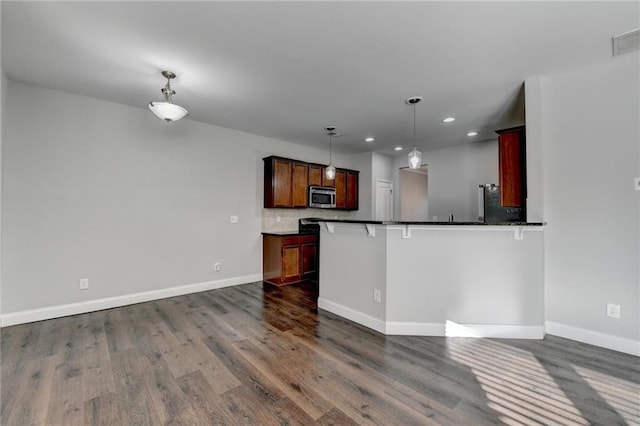 kitchen with dark wood-style floors, stainless steel microwave, dark countertops, and baseboards