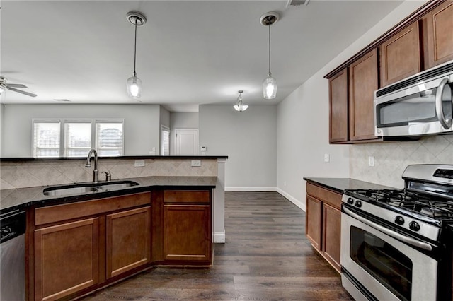 kitchen featuring stainless steel appliances, pendant lighting, a sink, and dark wood-style floors