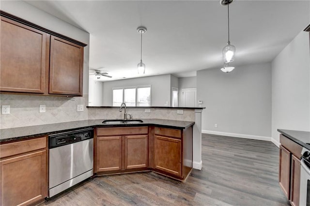 kitchen with dishwasher, dark countertops, a peninsula, a sink, and backsplash