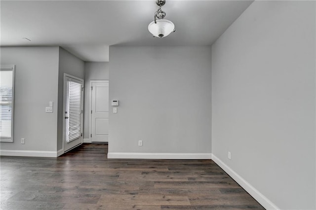 spare room with baseboards and wood finished floors