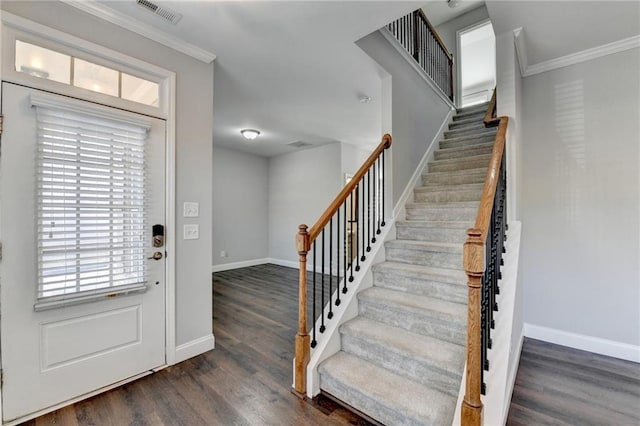 entrance foyer featuring crown molding, visible vents, wood finished floors, baseboards, and stairs