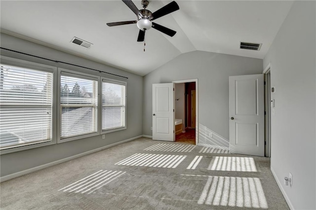 unfurnished bedroom featuring carpet, visible vents, lofted ceiling, and baseboards