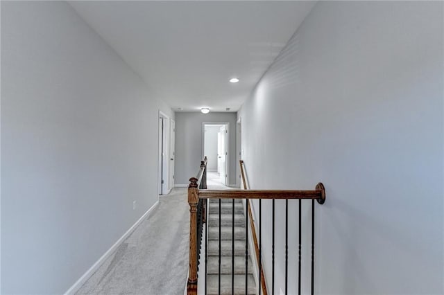 corridor with light carpet, an upstairs landing, and baseboards