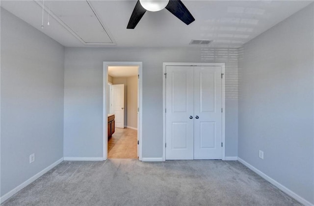 unfurnished bedroom featuring a closet, visible vents, attic access, light carpet, and baseboards