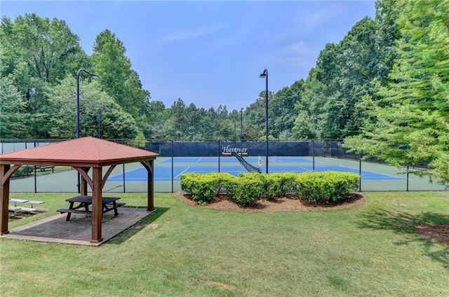 view of tennis court featuring fence and a lawn