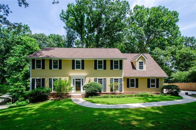 colonial house featuring a front yard and fence