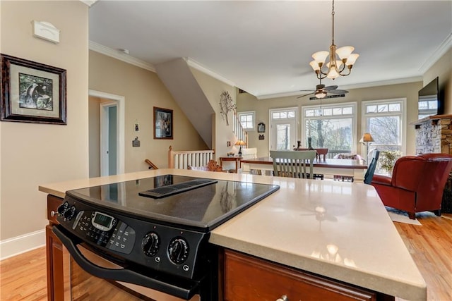 kitchen with light hardwood / wood-style floors, a stone fireplace, crown molding, electric range, and ceiling fan with notable chandelier