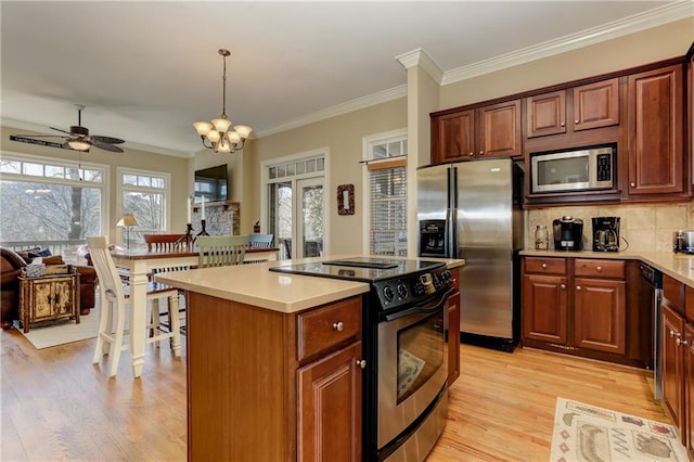 kitchen featuring light hardwood / wood-style floors, stainless steel appliances, ornamental molding, and hanging light fixtures