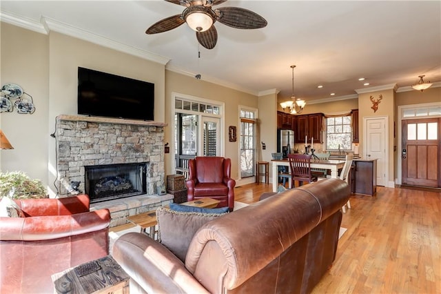 living room with crown molding, a stone fireplace, and light wood-type flooring