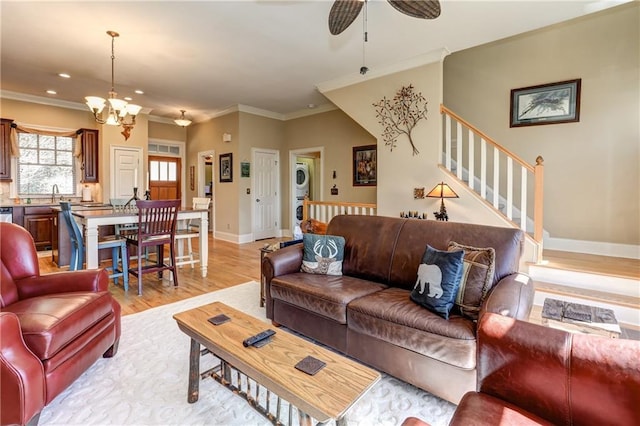 living room featuring light hardwood / wood-style floors, ornamental molding, sink, and ceiling fan with notable chandelier