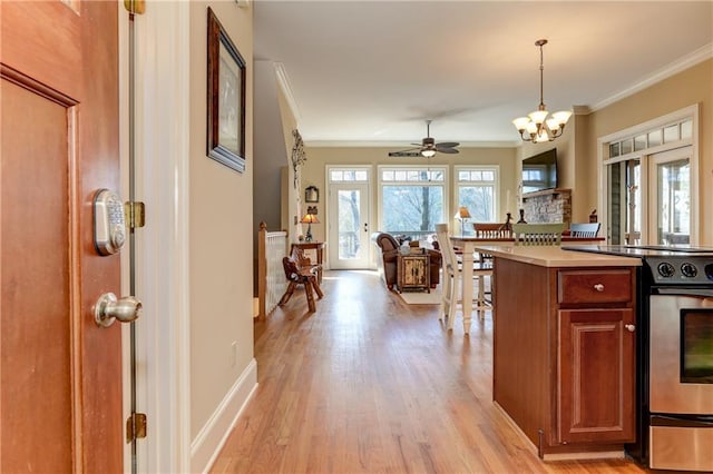 kitchen featuring ceiling fan with notable chandelier, hanging light fixtures, light hardwood / wood-style floors, stainless steel stove, and ornamental molding