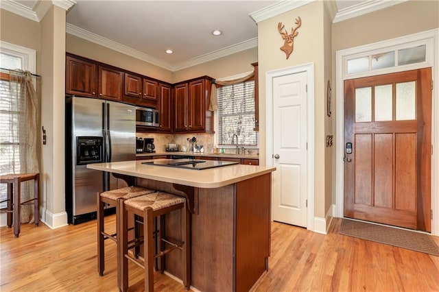 kitchen with light hardwood / wood-style flooring, backsplash, crown molding, a center island, and appliances with stainless steel finishes