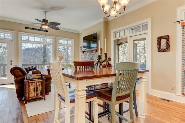 dining room featuring light hardwood / wood-style floors, crown molding, and ceiling fan with notable chandelier