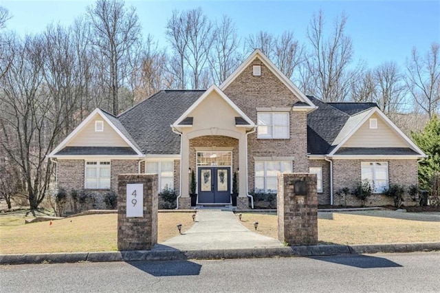 view of front of home with french doors, a front lawn, a shingled roof, and brick siding