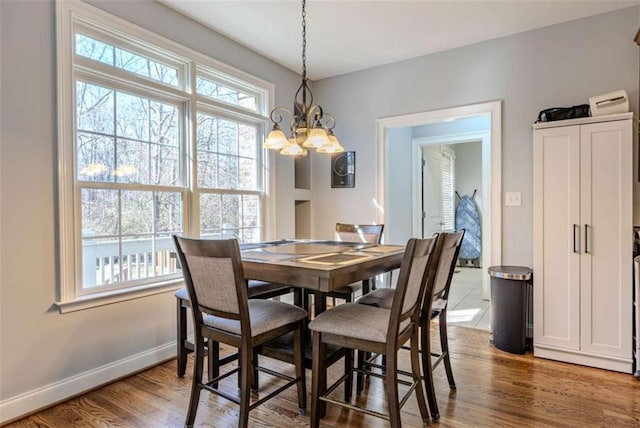 dining area featuring plenty of natural light, baseboards, a chandelier, and wood finished floors