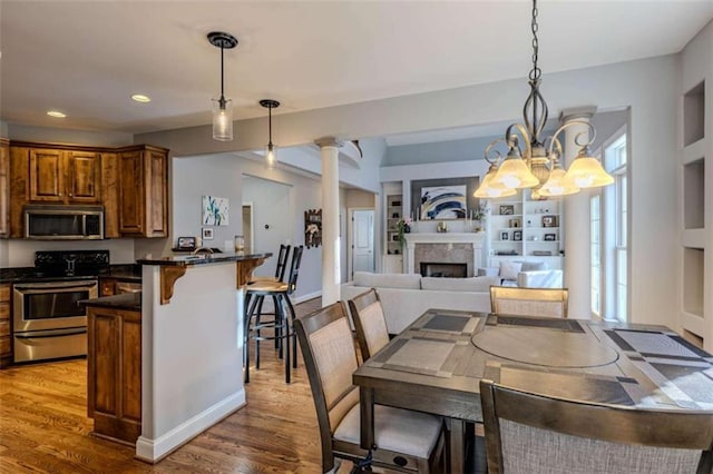 dining space with ornate columns, a fireplace, wood finished floors, and recessed lighting