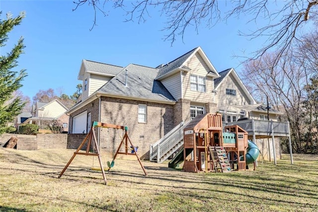 back of house with a playground, a yard, brick siding, roof with shingles, and an attached garage