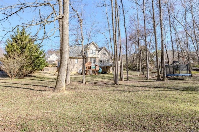 view of yard featuring stairs, a trampoline, and a wooden deck