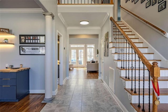 tiled entryway featuring decorative columns, visible vents, baseboards, ornamental molding, and french doors