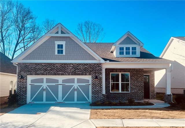 craftsman-style home with brick siding, an attached garage, roof with shingles, and driveway