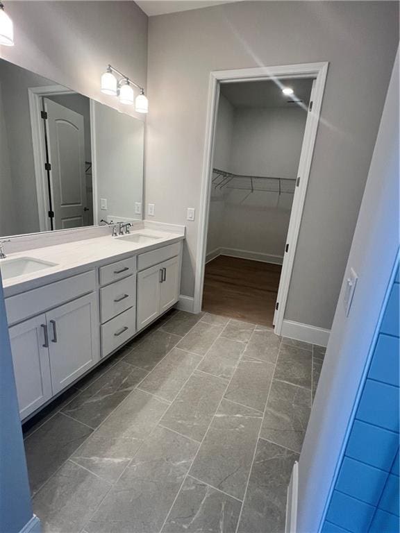 full bath with baseboards, a sink, and double vanity