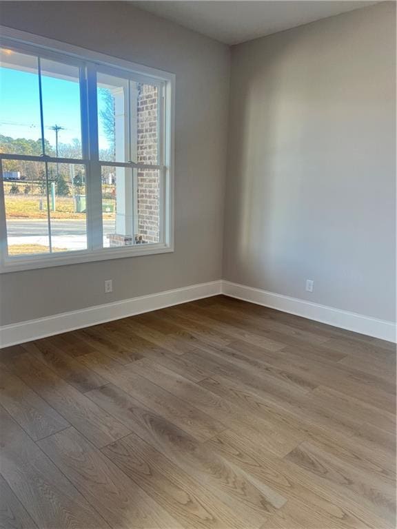unfurnished room featuring baseboards, a healthy amount of sunlight, and light wood-style flooring