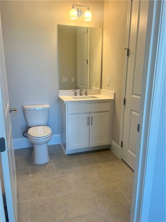 bathroom featuring baseboards, vanity, and toilet