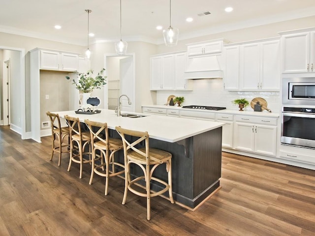 kitchen featuring visible vents, decorative backsplash, custom exhaust hood, a sink, and stainless steel appliances