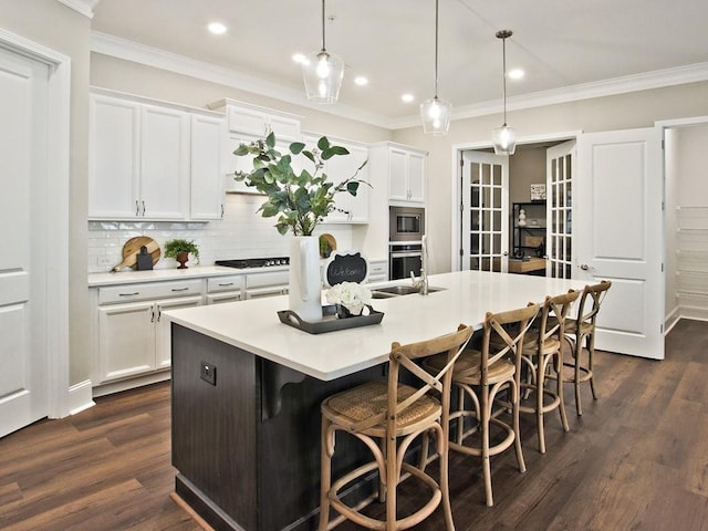 kitchen with decorative backsplash, an island with sink, a breakfast bar area, white cabinetry, and appliances with stainless steel finishes
